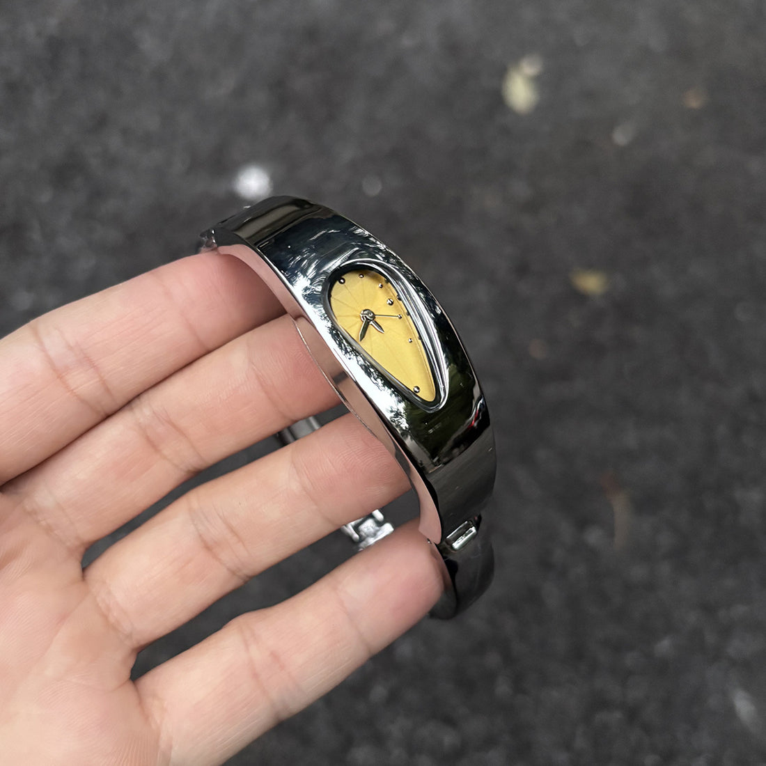 Golden dial water drop watch held in hand, outdoor lifestyle shot