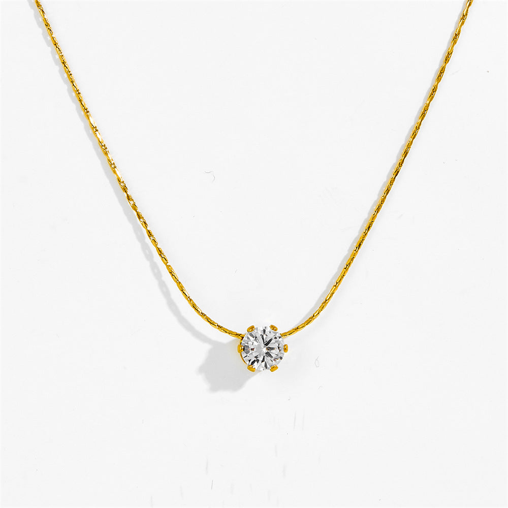 Gold-tone six claw pendant necklace laid flat, clear stone pendant detail