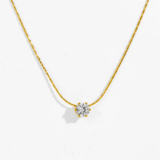 Gold-tone six claw pendant necklace laid flat, clear stone pendant detail