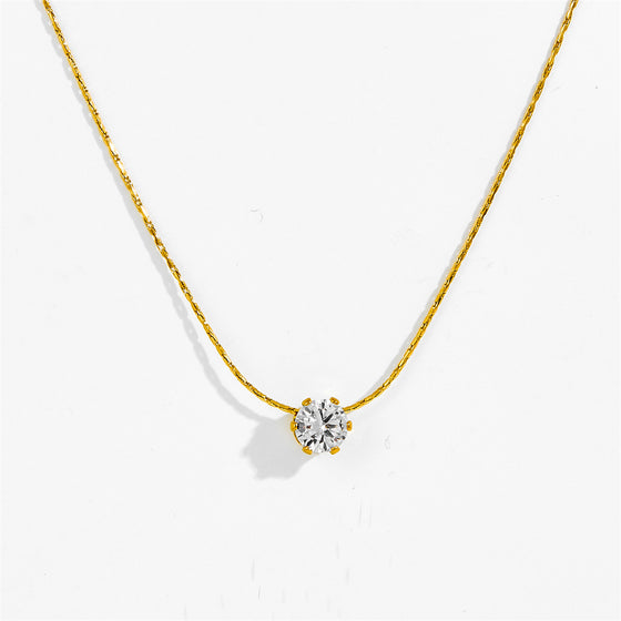 Gold-tone six claw pendant necklace laid flat, clear stone pendant detail