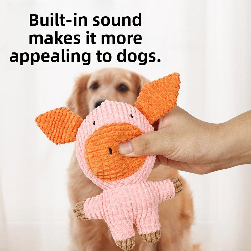 Hand holding a pink corduroy plush pig dog toy with built-in squeaker in front of a golden retriever