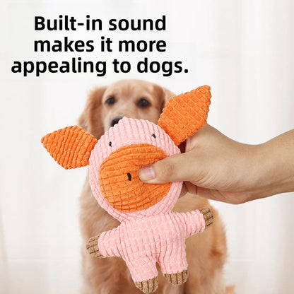Hand holding a pink corduroy plush pig dog toy with built-in squeaker in front of a golden retriever