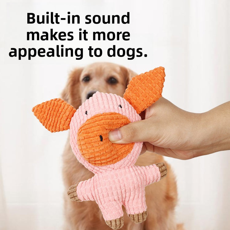 Hand holding a pink corduroy plush pig dog toy with built-in squeaker in front of a golden retriever
