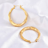 Top-down view of two wavy gold hoop earrings showing the hinged post closures