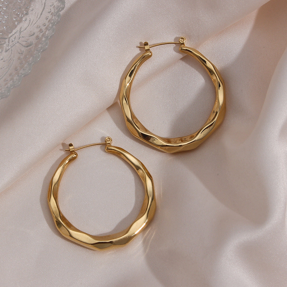 Close-up of gold-tone twisted rope hoop earrings showing the hinged post closure