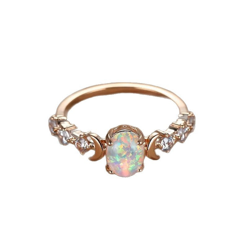 Top-down view of a rose gold-tone opal-style ring with crescent moon accents on a white background